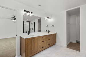 Full bath featuring double vanity, a shower stall, light carpet, a ceiling fan, and a walk in closet