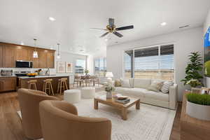 Living room with light wood-style floors, a ceiling fan, and recessed lighting