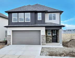 View of front of home featuring stone siding, an attached garage, concrete driveway, roof with shingles, and covered porch