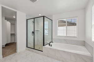 Bathroom with a shower stall, a garden tub, a walk in closet, and light marble finish floors