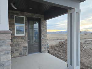 Property entrance featuring stone siding and a patio area