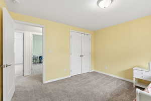 Unfurnished bedroom with light colored carpet and a closet