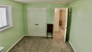Unfurnished bedroom with dark colored carpet and a closet