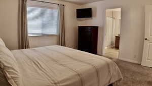 Bedroom featuring light carpet and ensuite bath