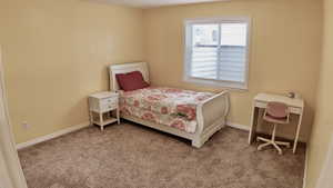 Bedroom featuring light carpet and baseboards
