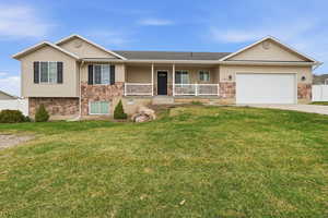 Ranch-style house with board and batten siding, covered porch, stone siding, and an attached garage