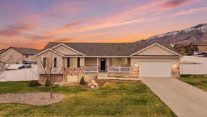 View of front of property with stone siding, a porch, driveway, a garage, and roof with shingles