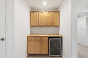 Bar area with wine cooler, butcher block counters, light wood finish cabinets, and electric panel