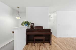 Hall with light wood finished floors and an upstairs landing