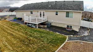 Rear view of house featuring a fenced backyard, a gate, a wooden deck, and roof with shingles
