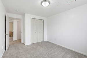 Unfurnished bedroom with light carpet and a closet