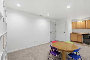 Dining space featuring light colored carpet, recessed lighting, bar, and wine cooler