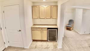Indoor dry bar featuring light carpet, light wood finish cabinets, wine cooler, and butcher block countertops