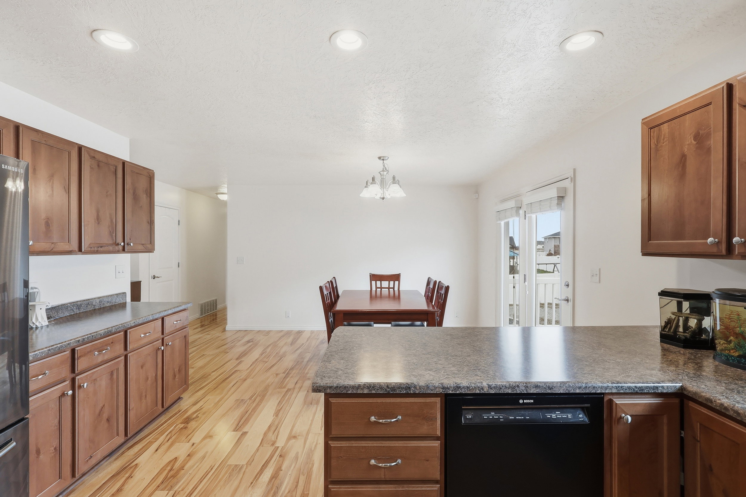 Kitchen featuring dark countertops, a peninsula, dishwasher, light wood-style flooring, and wood finish cabinets
