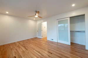 Primary bedroom featuring recessed lighting, Oak flooring, ceiling fan, and a closet with custom built-ins, opaque glass doors