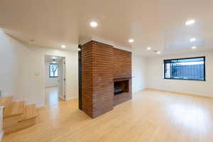 living room with bamboo flooring, a brick fireplace, and recessed lighting