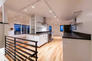 Kitchen featuring open shelves, white cabinets, solid oak flooring, stainless steel appliances, and track lighting