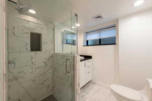 Ensuite bathroom featuring light marble shower and tile finish flooring, a marble finish shower, vanity, and recessed lighting