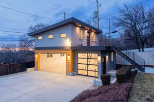 Contemporary carriage home featuring a balcony, stucco siding, driveway, and a garage w/ lift, 220 and 110 electrics