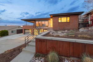 View of front of property featuring driveway and brick siding, solid rusted steel border