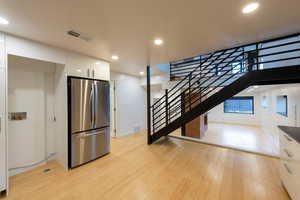Kitchen featuring GE Profile refrigerator, white cabinetry, bamboo flooring, recessed lighting, and modern cabinets
