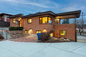 View of back of home featuring brick siding, a patio, and driveway