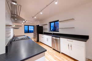 Kitchen featuring open shelves, light wood-style floors, track lighting, white cabinetry, and high end GE PROFILE stainless steel appliances