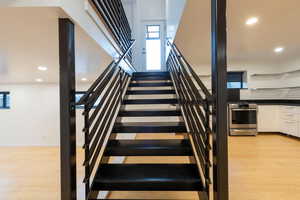 Stairs featuring recessed lighting, wood finished floors, plenty of natural light, and a high ceiling
