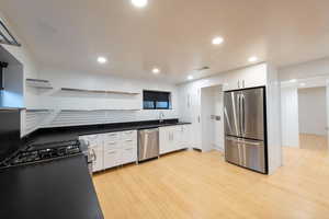 Kitchen featuring open shelves, stainless steel appliances, white cabinets,  and recessed lighting
