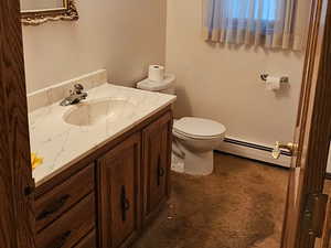 Half bathroom featuring vanity, dark carpet, baseboard heating, and crown molding