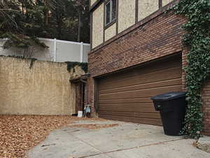 View of property exterior featuring brick, asphalt driveway, and an attached garage