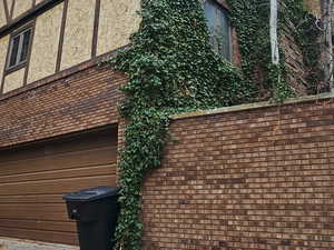 View of side of home featuring brick siding, an attached garage, and driveway