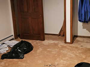 bedroom #6 featuring multiple closets, light colored carpet, and baseboard heating