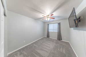 Carpeted empty room featuring a textured ceiling and ceiling fan