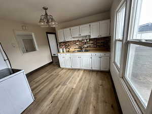 Kitchen with white cabinets, light countertops, light wood finished floors, washer / clothes dryer, and a chandelier