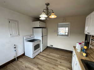 Kitchen with white appliances, white cabinetry, and light wood-style floors