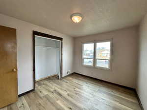 Unfurnished bedroom featuring light wood-style flooring, a closet, and a textured ceiling