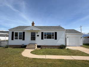 View of front of property featuring an attached garage, a chimney, a shingled roof, driveway, and entry steps