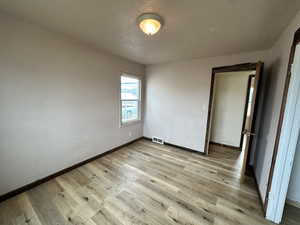 Unfurnished bedroom with light wood finished floors and baseboards