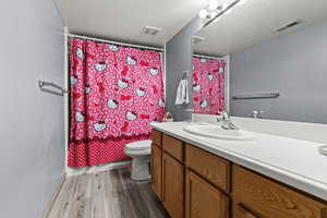 Bathroom featuring vanity, dark wood-type flooring, a textured ceiling, and shower / bath combo