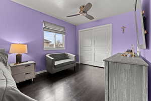 Bedroom with dark wood-style flooring, a ceiling fan, and a closet