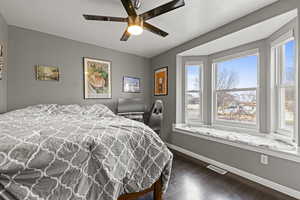 Bedroom with dark wood-style floors, ceiling fan, and a textured ceiling