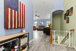 Corridor featuring an upstairs landing, wood finished floors, and arched walkways