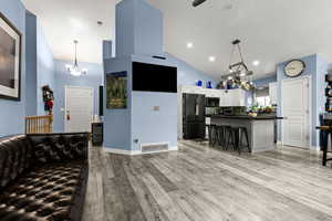 Kitchen with a chandelier, dark countertops, vaulted ceiling, freestanding refrigerator, and light wood finished floors
