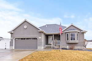 Single story home with concrete driveway, stucco siding, a garage, roof with shingles, and covered porch