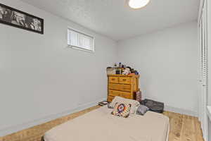 Bedroom with light wood-type flooring and a textured ceiling