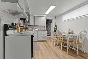 Kitchen featuring white range oven, decorative backsplash, gray cabinets, light wood-style flooring, and a textured ceiling