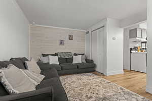 Living area featuring wooden walls, light wood-style floors, and crown molding