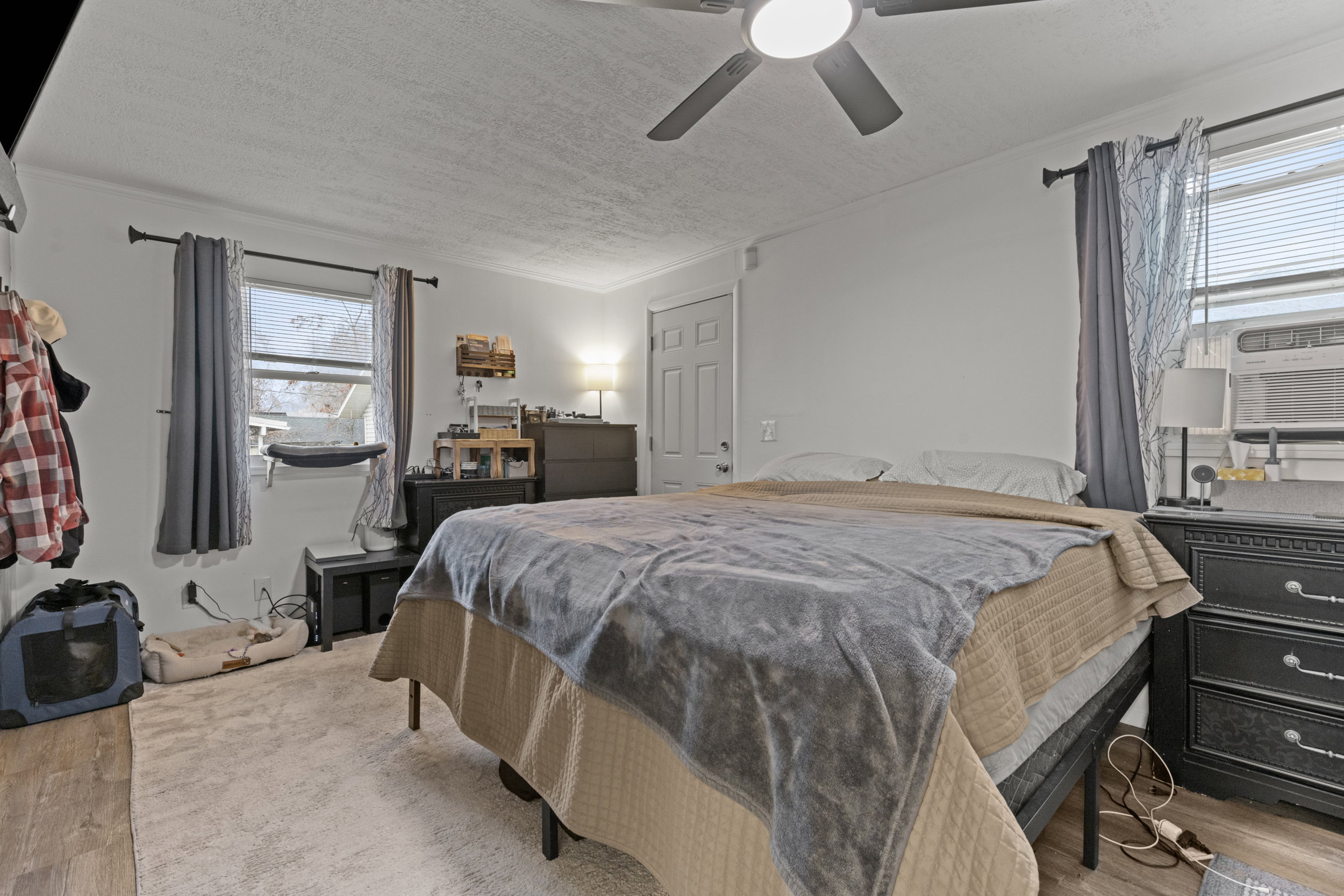 Bedroom featuring light wood-style flooring, ceiling fan, a textured ceiling, crown molding, and cooling unit