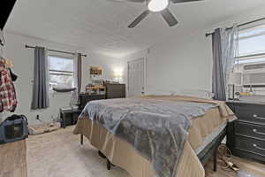 Bedroom featuring light wood-style flooring, ceiling fan, a textured ceiling, crown molding, and cooling unit